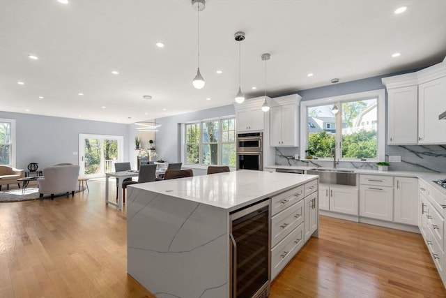 kitchen featuring a sink, white cabinets, wine cooler, recessed lighting, and light wood-style flooring