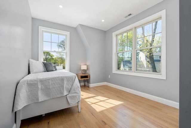bedroom featuring baseboards, multiple windows, light wood-style flooring, and visible vents