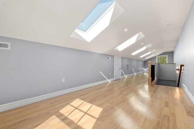 bonus room with vaulted ceiling with skylight, baseboards, wood finished floors, and visible vents