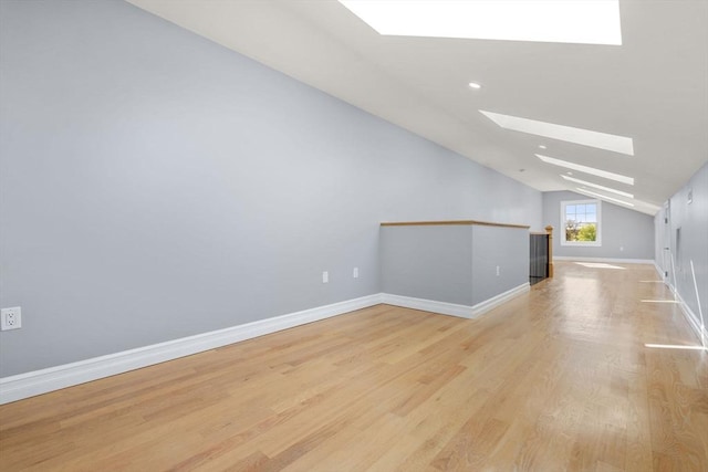additional living space featuring recessed lighting, baseboards, vaulted ceiling with skylight, and light wood-type flooring