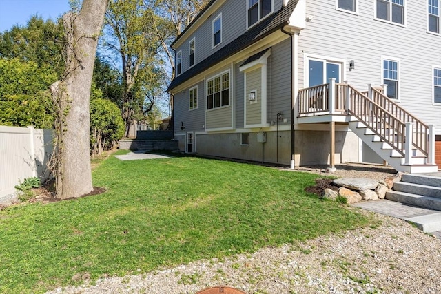 view of side of property with a lawn, fence, and stairs