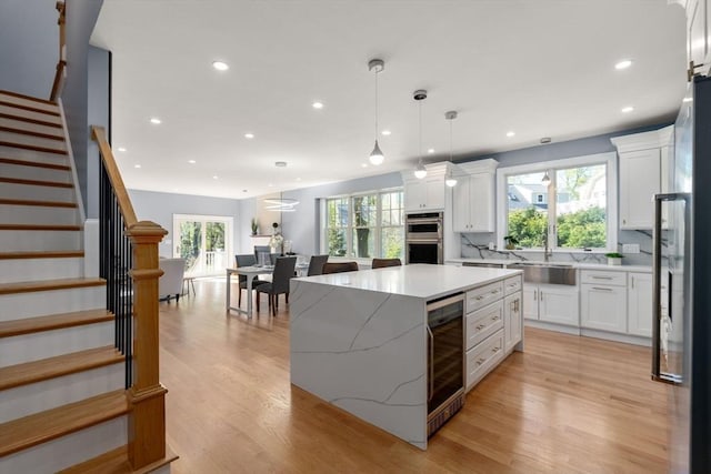 kitchen with recessed lighting, a sink, white cabinetry, and wine cooler