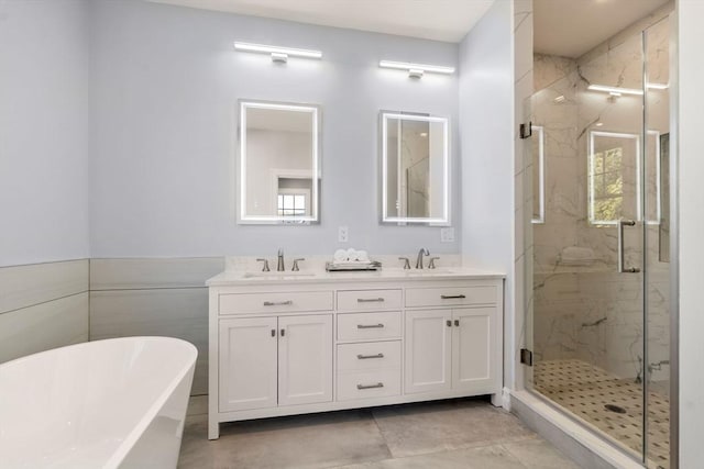 bathroom featuring a sink, a marble finish shower, a soaking tub, and double vanity