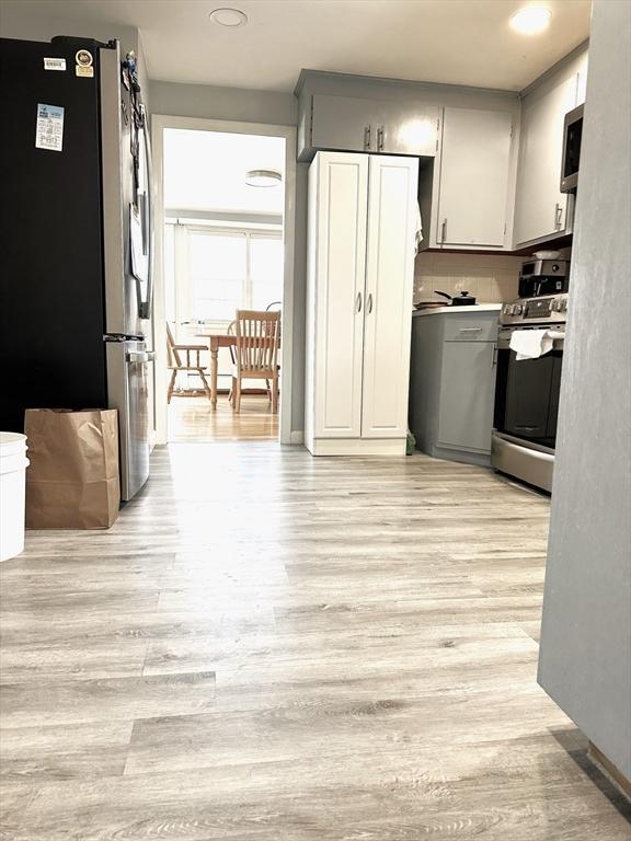 kitchen featuring decorative backsplash, light wood-style flooring, and appliances with stainless steel finishes