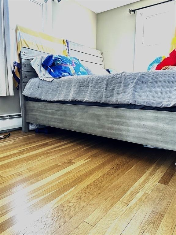 bedroom featuring a baseboard heating unit and wood finished floors