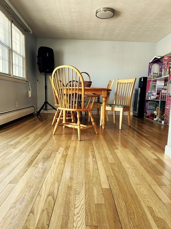 dining area featuring baseboard heating, a textured ceiling, and wood-type flooring