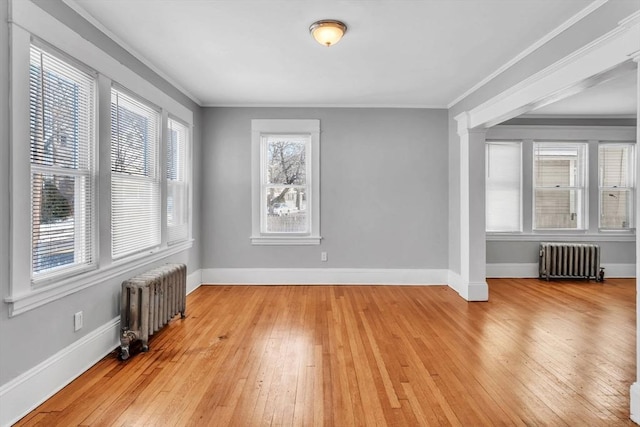 empty room featuring radiator, ornate columns, and light wood-style flooring