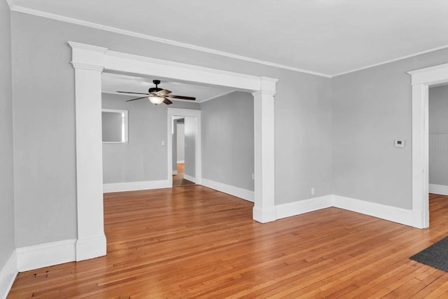 spare room featuring crown molding, ornate columns, light wood-style floors, ceiling fan, and baseboards