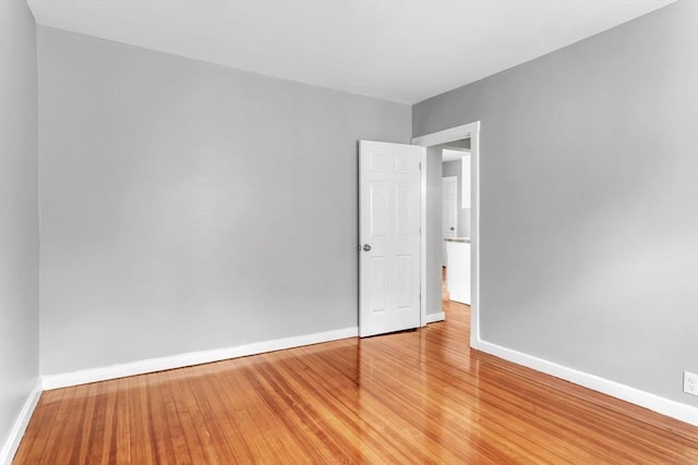 spare room featuring baseboards and wood finished floors