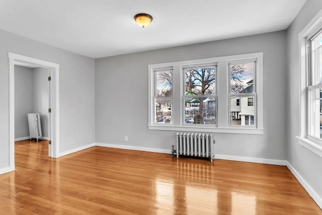 spare room featuring radiator, light wood-style flooring, and a wealth of natural light