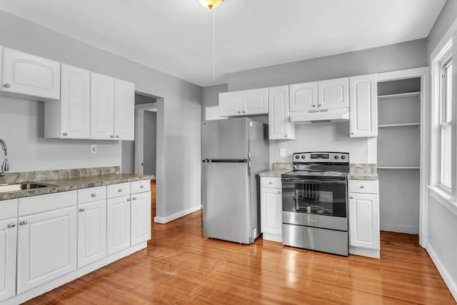 kitchen with white cabinets, light wood-style floors, appliances with stainless steel finishes, under cabinet range hood, and a sink