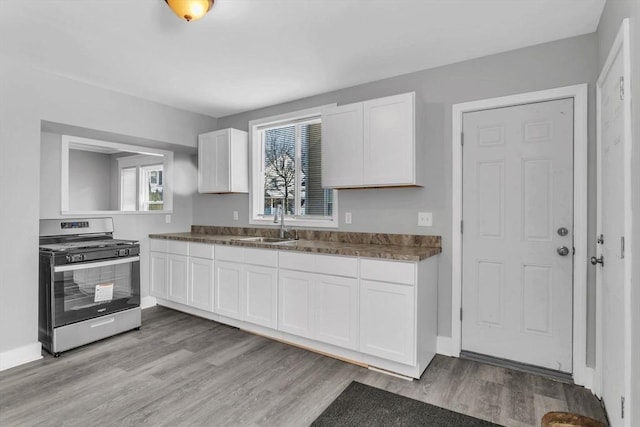 kitchen featuring light wood-style floors, gas stove, a sink, and white cabinets