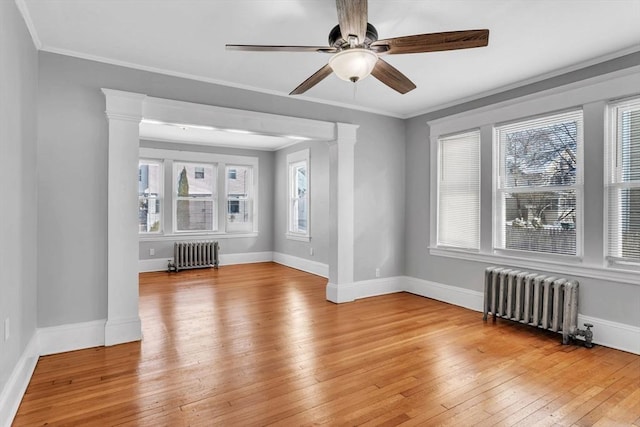 unfurnished room with ornate columns, light wood-style floors, crown molding, and radiator