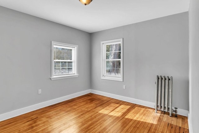 spare room with baseboards, a healthy amount of sunlight, light wood-type flooring, and radiator