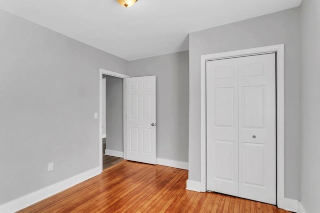 unfurnished bedroom with light wood finished floors, baseboards, and a closet