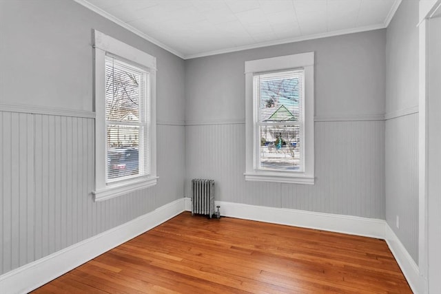 spare room featuring ornamental molding, wainscoting, hardwood / wood-style floors, and radiator heating unit