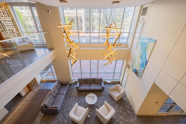 carpeted living room with visible vents and a high ceiling
