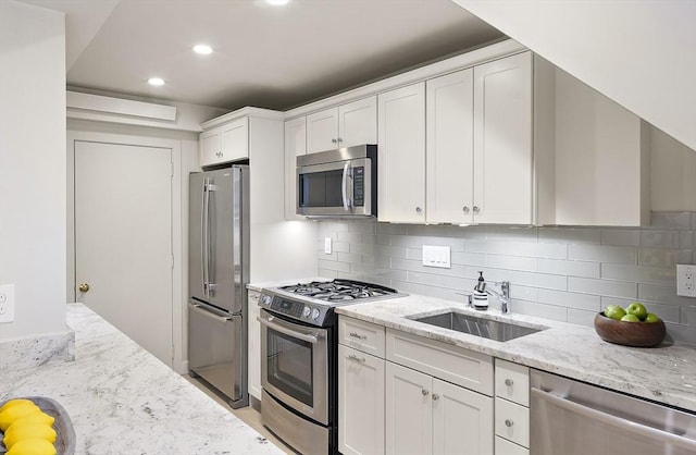 kitchen with stainless steel appliances, a sink, white cabinetry, light stone countertops, and recessed lighting