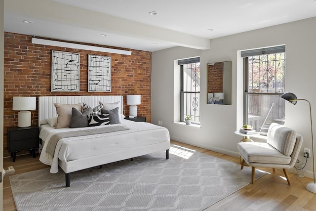 bedroom featuring light wood-style floors, baseboards, and beamed ceiling