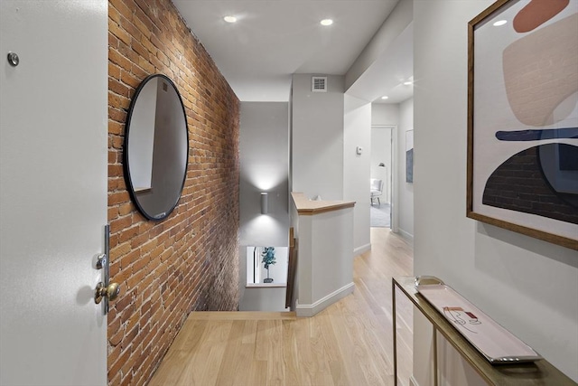hall with brick wall, light wood finished floors, baseboards, and recessed lighting