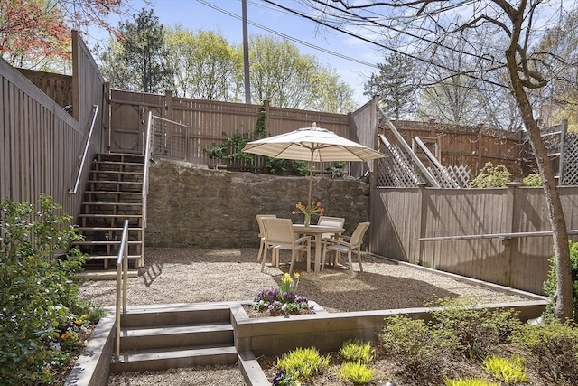 view of patio featuring stairway, a fenced backyard, and outdoor dining area