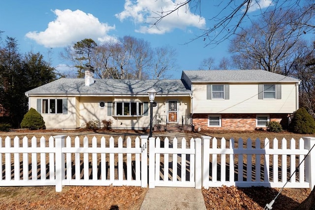 split level home featuring a fenced front yard, brick siding, driveway, and a chimney