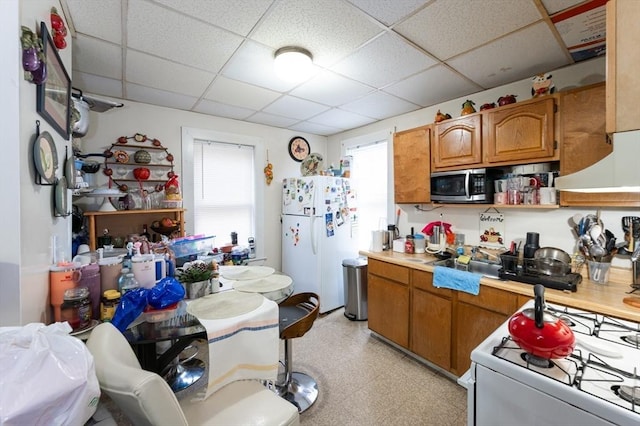 8 Everett St, Somerville, MA 02143 - kitchen with white appliances, light countertops, a paneled ceiling, brown cabinetry, and light flooring