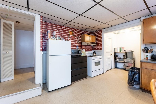 8 Everett St, Somerville, MA 02143 - kitchen with white appliances, a paneled ceiling, brick wall, under cabinet range hood, and light floors