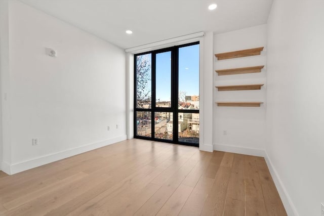 unfurnished room with expansive windows and light hardwood / wood-style flooring