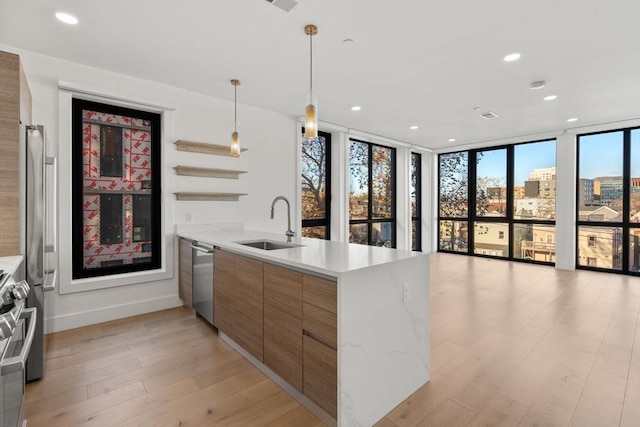 kitchen with sink, light wood-type flooring, decorative light fixtures, a wall of windows, and kitchen peninsula