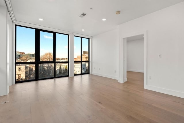 unfurnished room featuring light hardwood / wood-style floors and a wall of windows