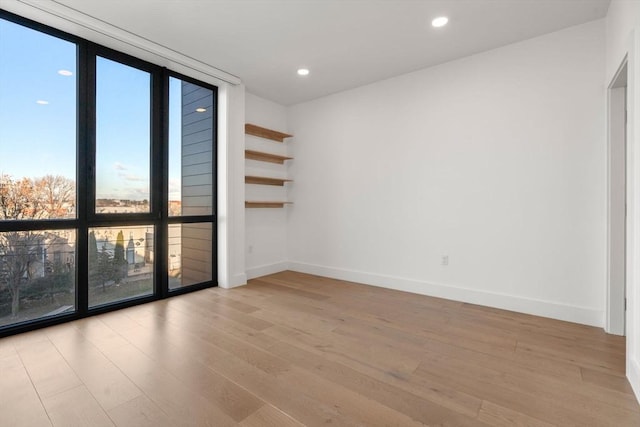 unfurnished room featuring a wall of windows and light hardwood / wood-style flooring