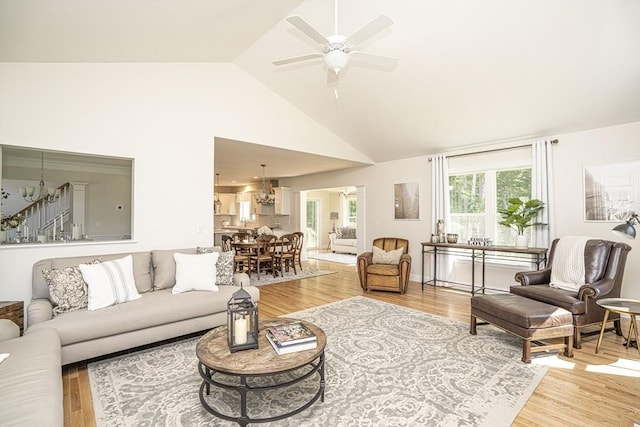 living room with lofted ceiling, ceiling fan with notable chandelier, and hardwood / wood-style flooring