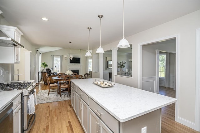 kitchen with pendant lighting, white cabinets, appliances with stainless steel finishes, a kitchen island, and light hardwood / wood-style flooring