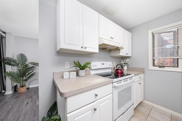 kitchen featuring light hardwood / wood-style flooring, white electric range oven, and white cabinets