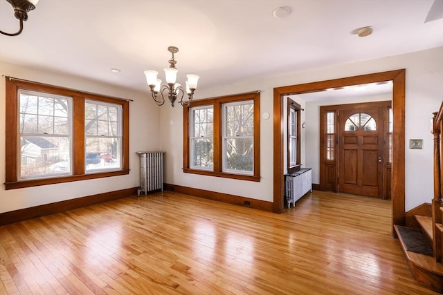 foyer entrance featuring an inviting chandelier, radiator heating unit, baseboards, and light wood-style flooring