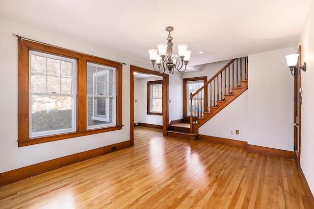 interior space featuring baseboards, stairway, light wood finished floors, and an inviting chandelier