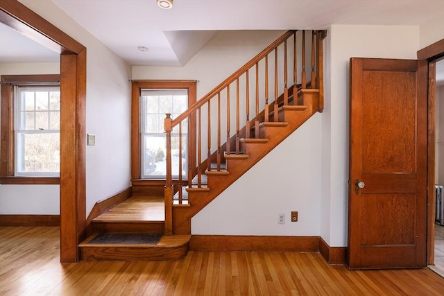 stairs with plenty of natural light, wood finished floors, and baseboards