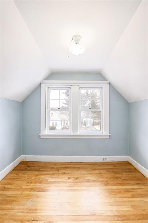 bonus room with light wood-type flooring, lofted ceiling, and baseboards