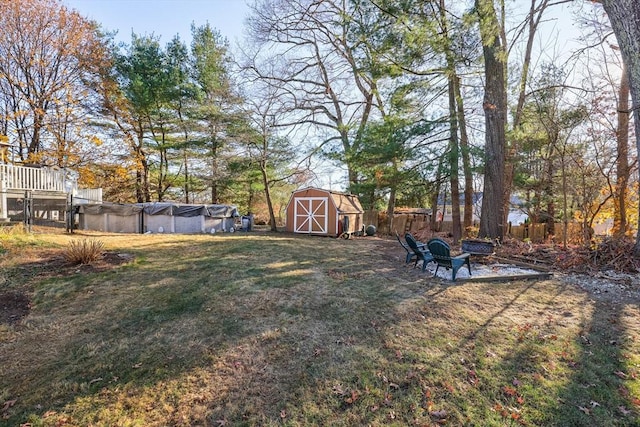 view of yard with an outdoor fire pit, a covered pool, fence, an outdoor structure, and a shed