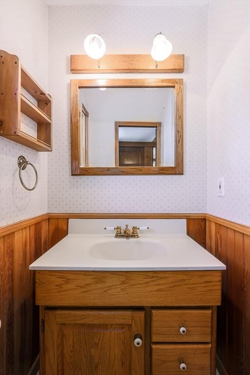 bathroom featuring wainscoting, vanity, and wallpapered walls