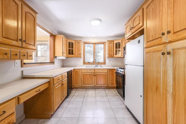 kitchen featuring glass insert cabinets, black range, light countertops, and a sink