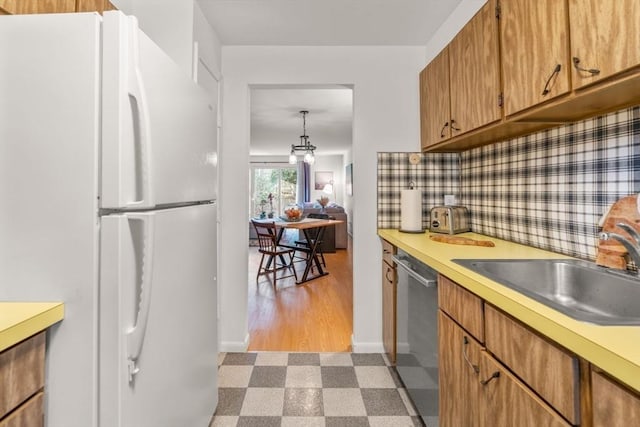 kitchen with sink, stainless steel dishwasher, white refrigerator, backsplash, and light wood-type flooring