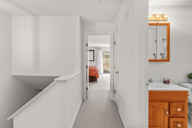 corridor featuring light carpet and sink