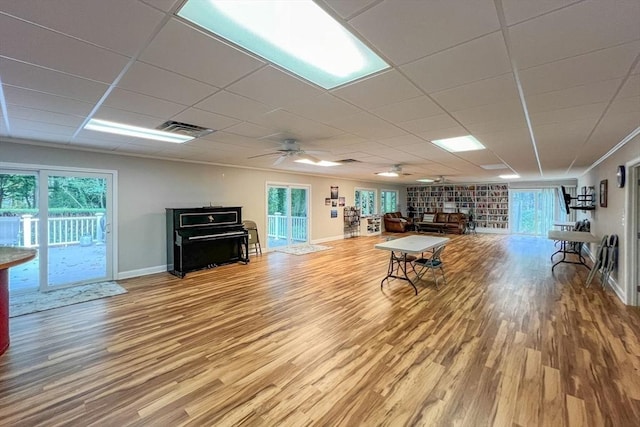 living room featuring wood-type flooring, a paneled ceiling, ceiling fan, and crown molding