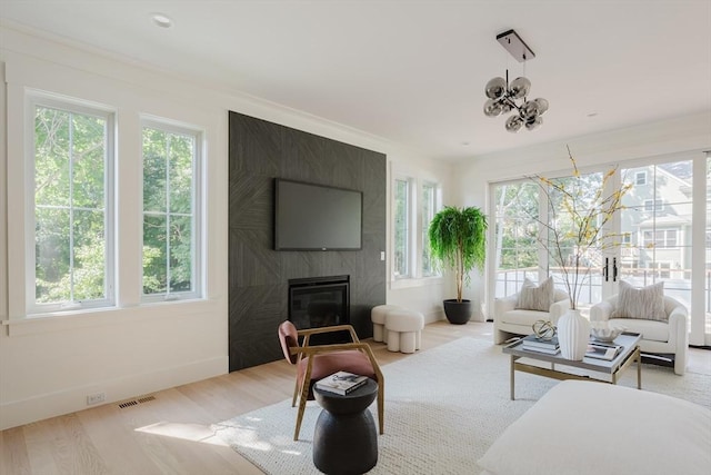 living room with a large fireplace, light hardwood / wood-style floors, and a notable chandelier