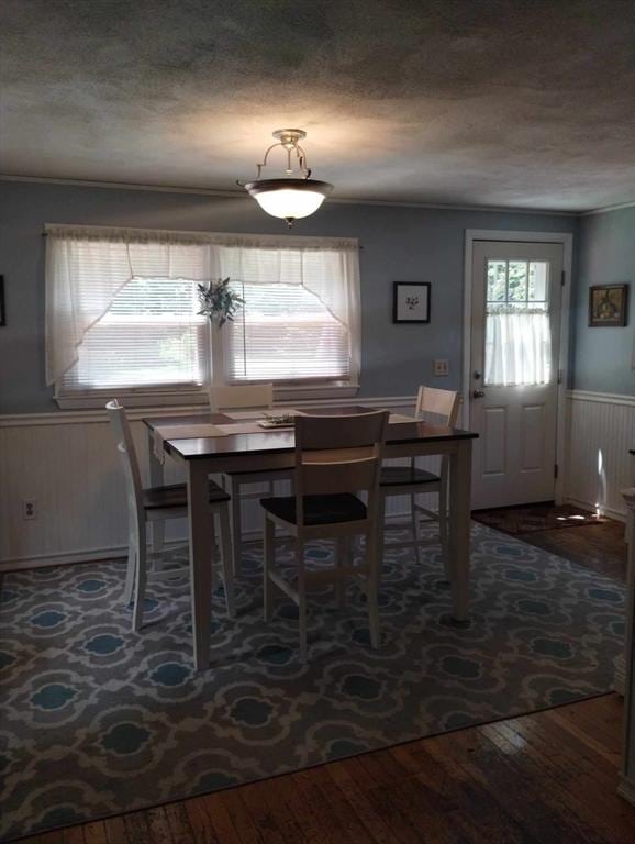 dining area with hardwood / wood-style flooring, a textured ceiling, and wood walls