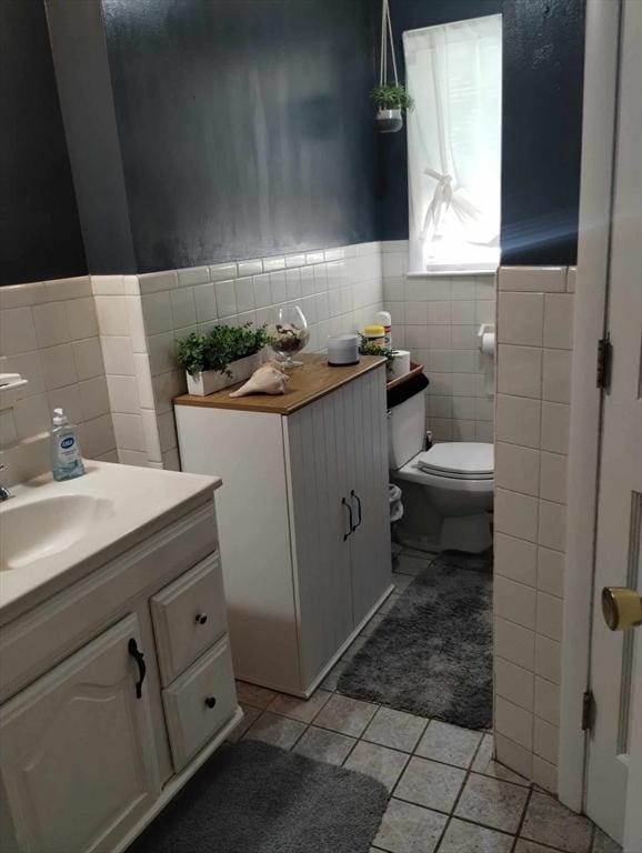 bathroom with tile patterned flooring, vanity, tile walls, and toilet