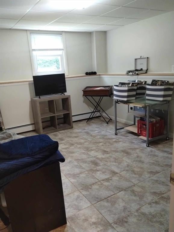 interior space featuring baseboard heating and a drop ceiling