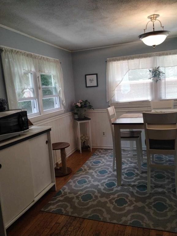 dining room featuring crown molding, wood-type flooring, and a textured ceiling